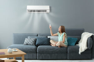 young woman on the lounge switching on the split system air conditioner with remote control